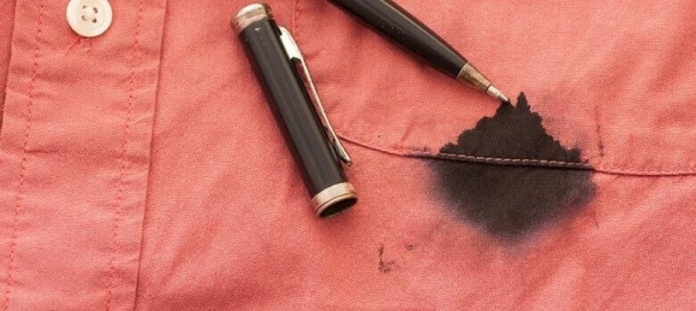 Camisa roja manchada por un bolígrafo abierto de tinta negra